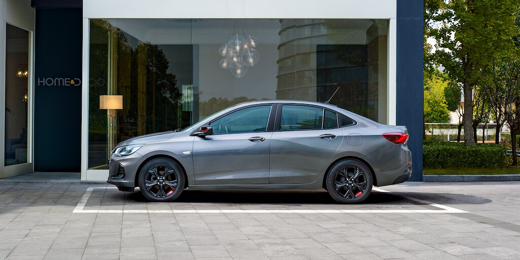 Chevrolet Onix 2023, sedán deportivo equipado con rines negros con detalle en rojo y manijas exteriores al color de la carrocería